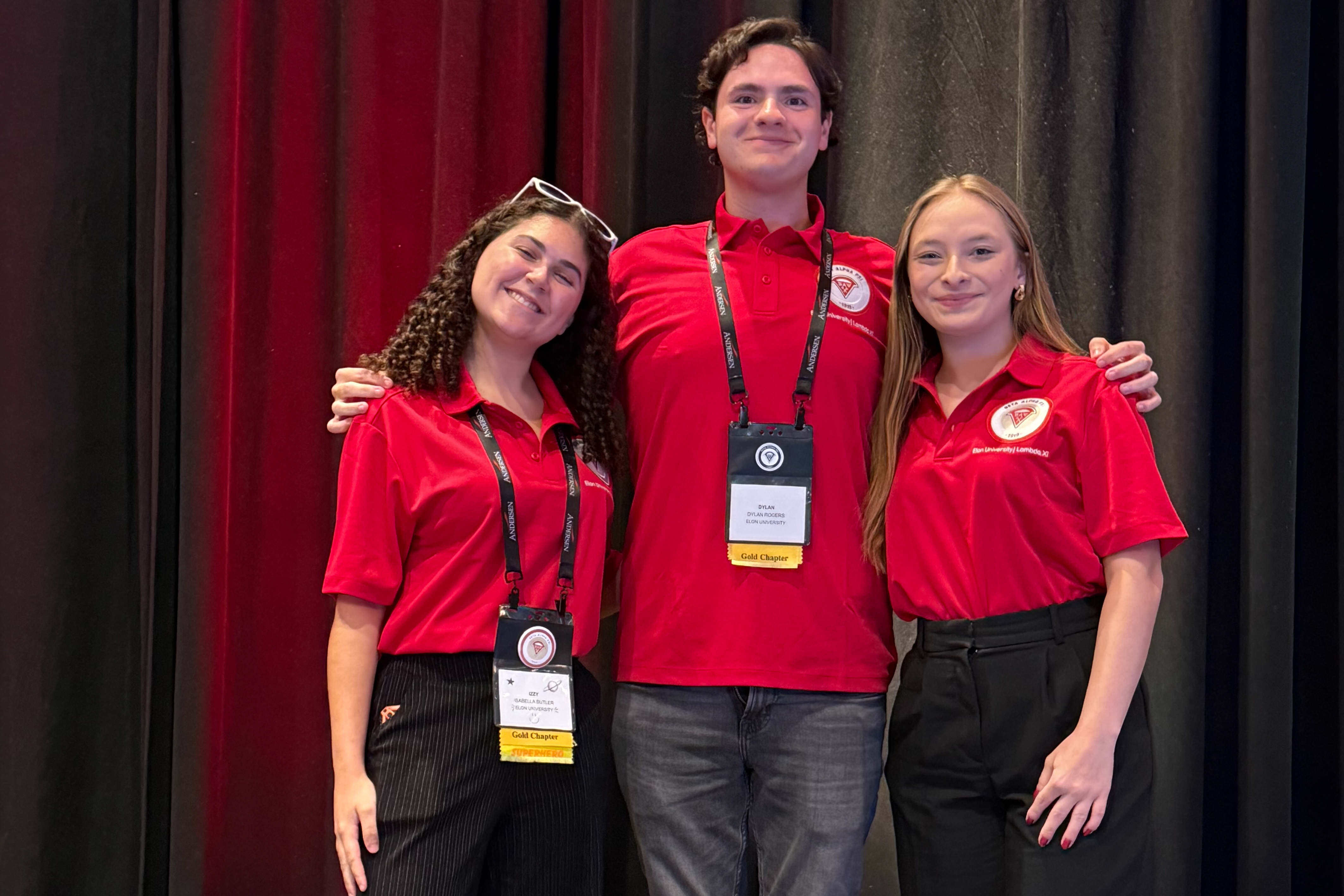 Izzy Butler, Dylan Rogers and Kaitlyn Niestoeckel stand together in matching red ���ϲ����� Beta Alpha Psi shirts at the organization’s annual meeting in Baltimore.