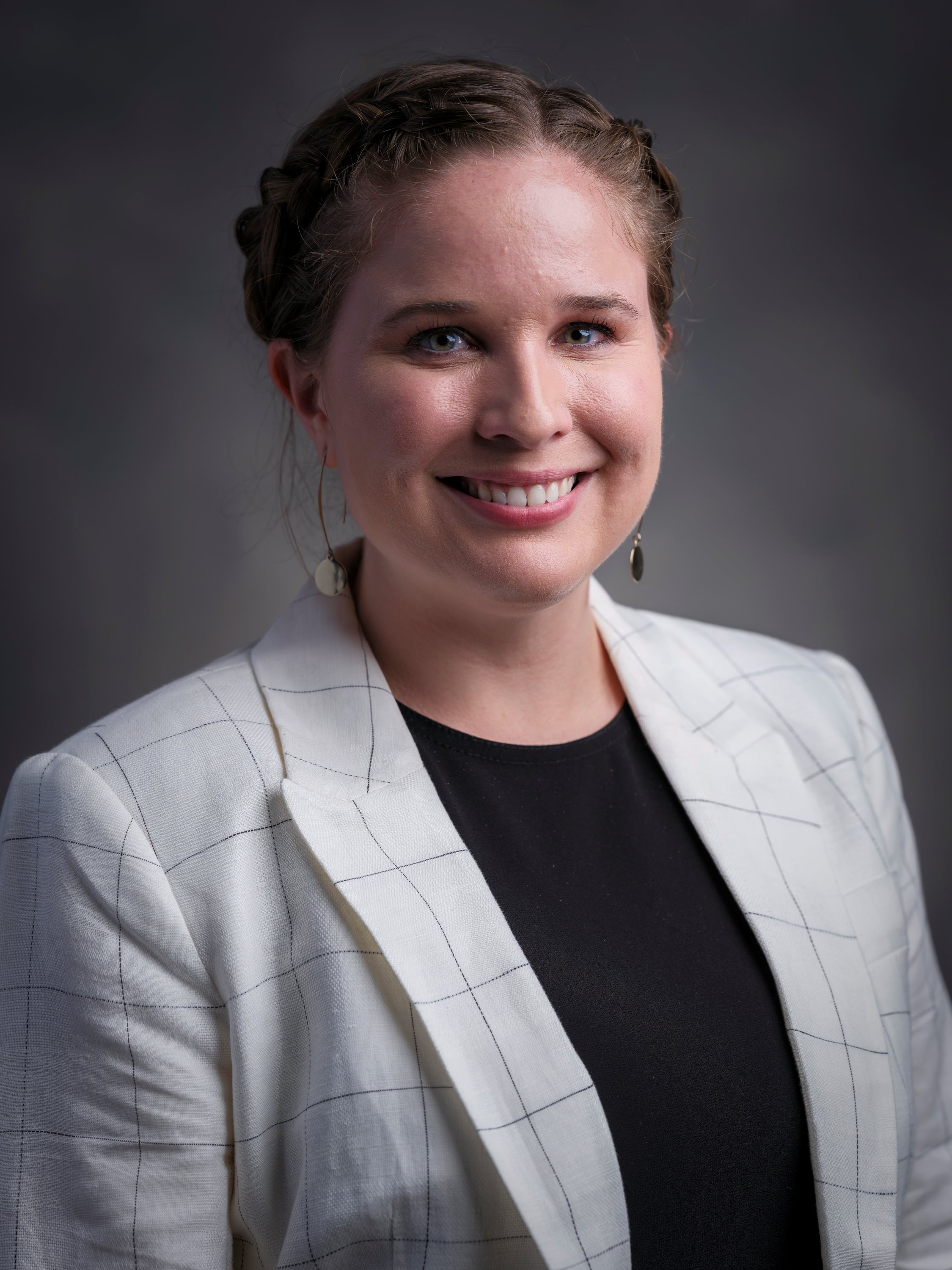 A headshot of Olivia Cox on a gray background
