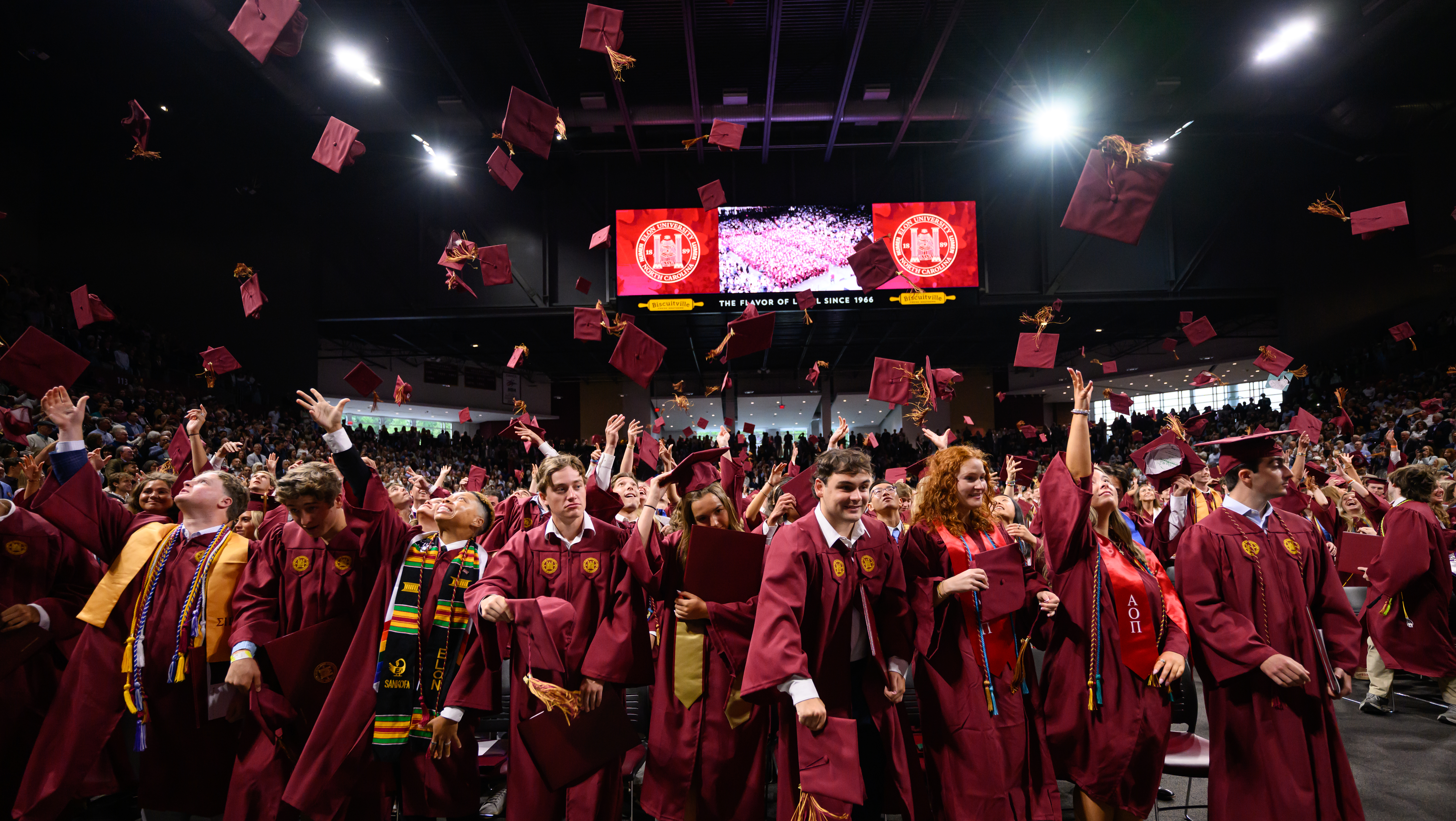 graduates throw caps in the air at Commencement