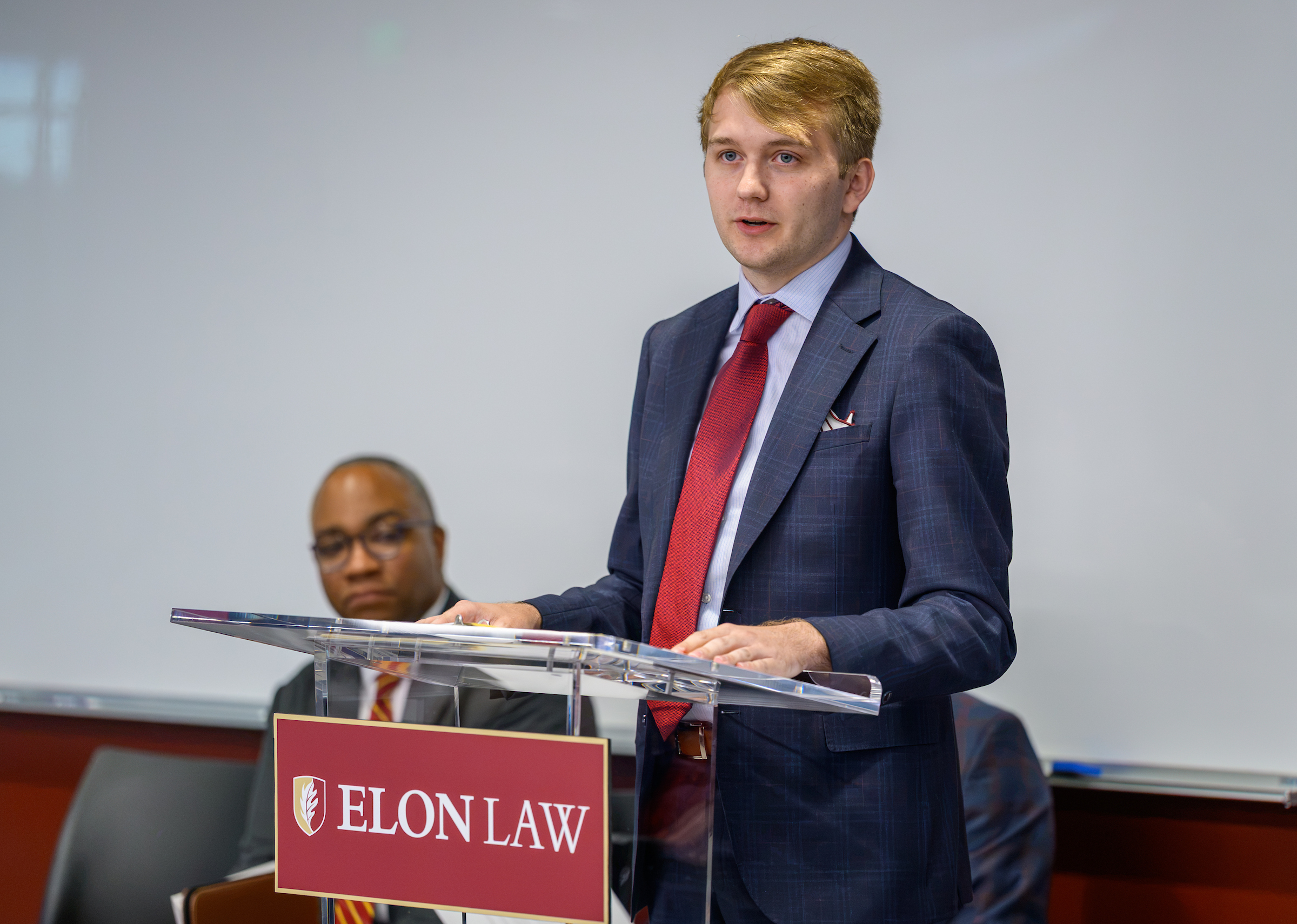 A person speaks at a podium with an ������Ƶ Law plaquard on it.