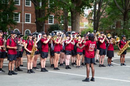 Students in the band wearing red band t-shirts holding their instruments and performing on move in day.