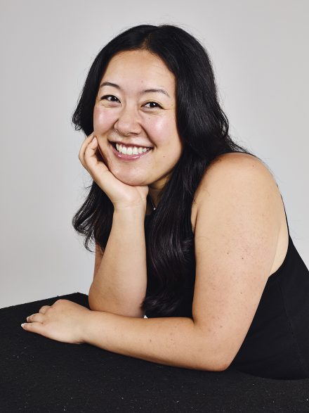 Joyce Choi smiles for a headshot with her hand on her face.