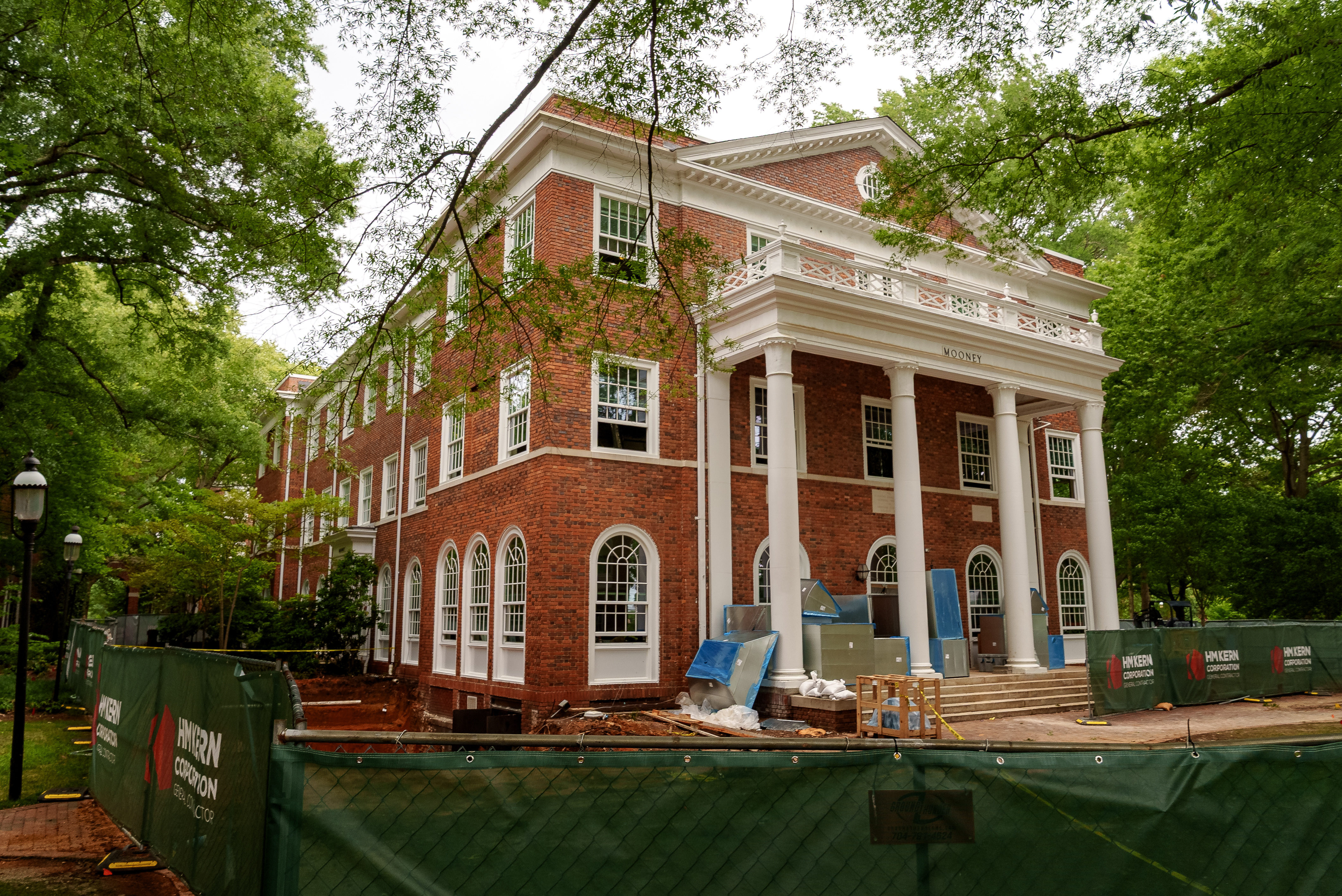 The historic Mooney Building stands surrounded by construction fencing as exterior renovations continue. New windows, restored brickwork and construction materials are visible around the building.