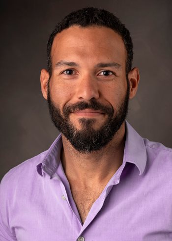 Headshot of Efrain Rivera-Serrano wearing a pink button up shirt. 