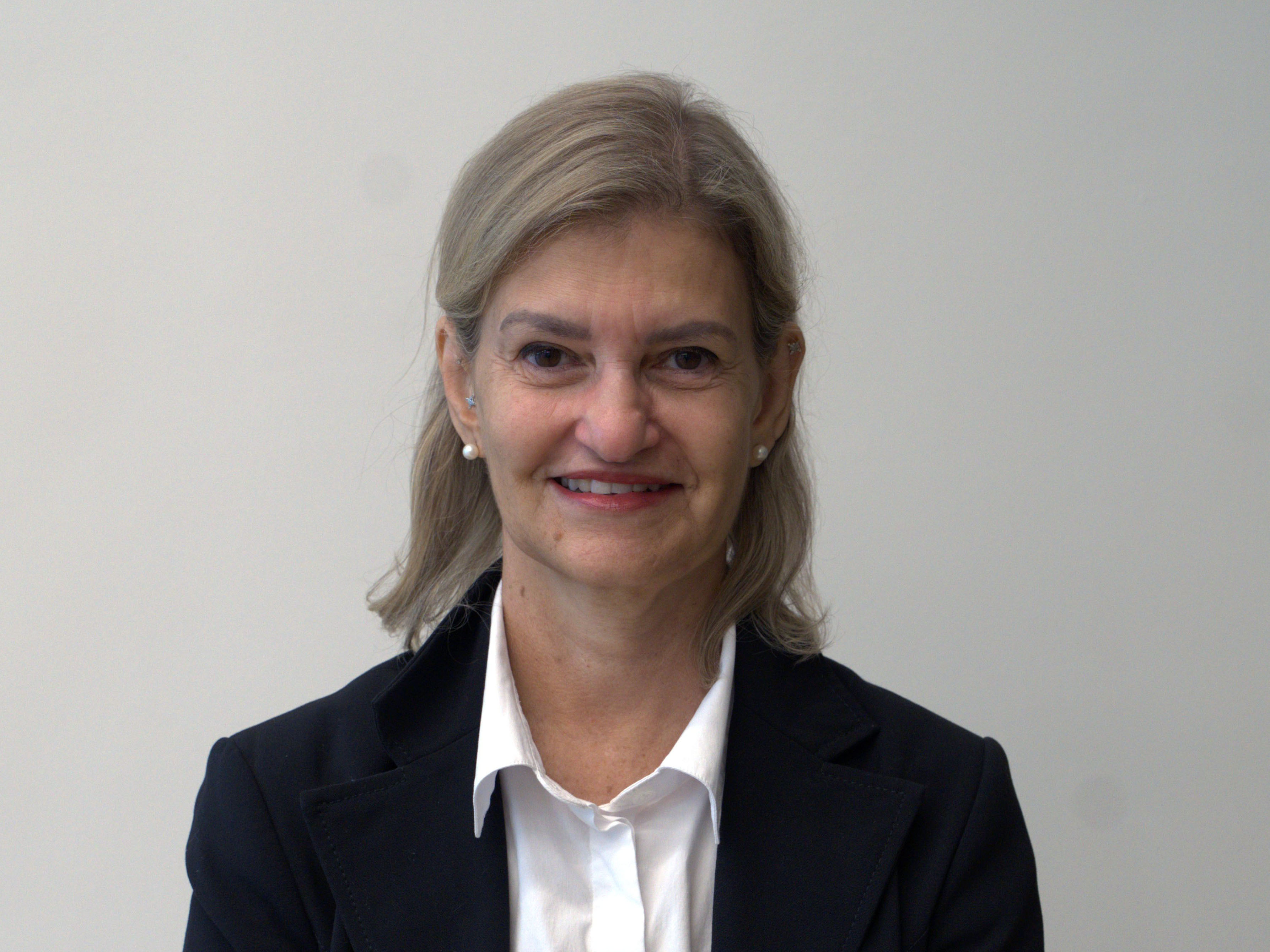 HEadshot of a woman with blonde hair, white shirt and navy blazer.