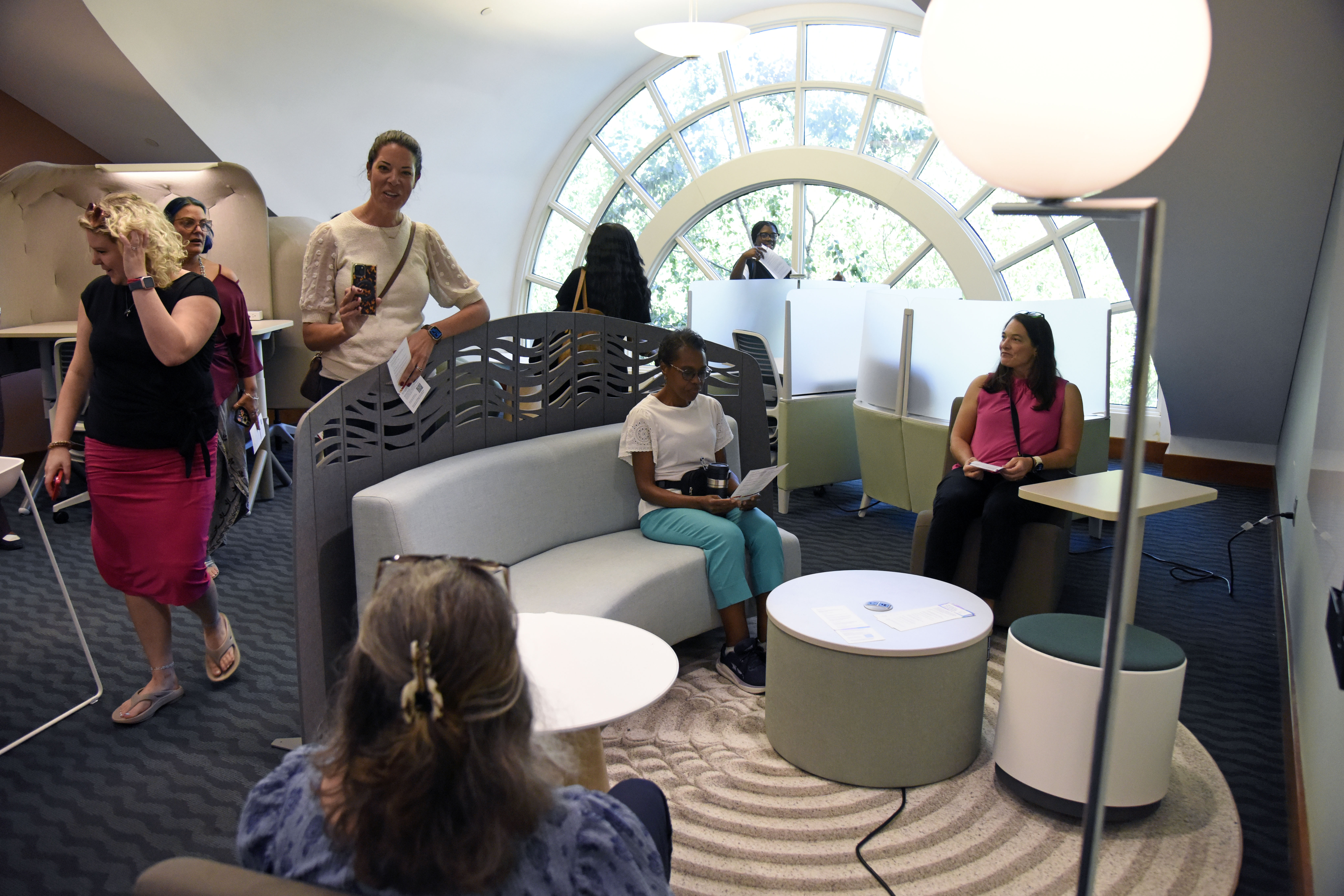 A photo of Elon staff members in a study space on the third floor of Belk LIbrary with a large window overlooking a lawn and movable furntiure in the foreground.
