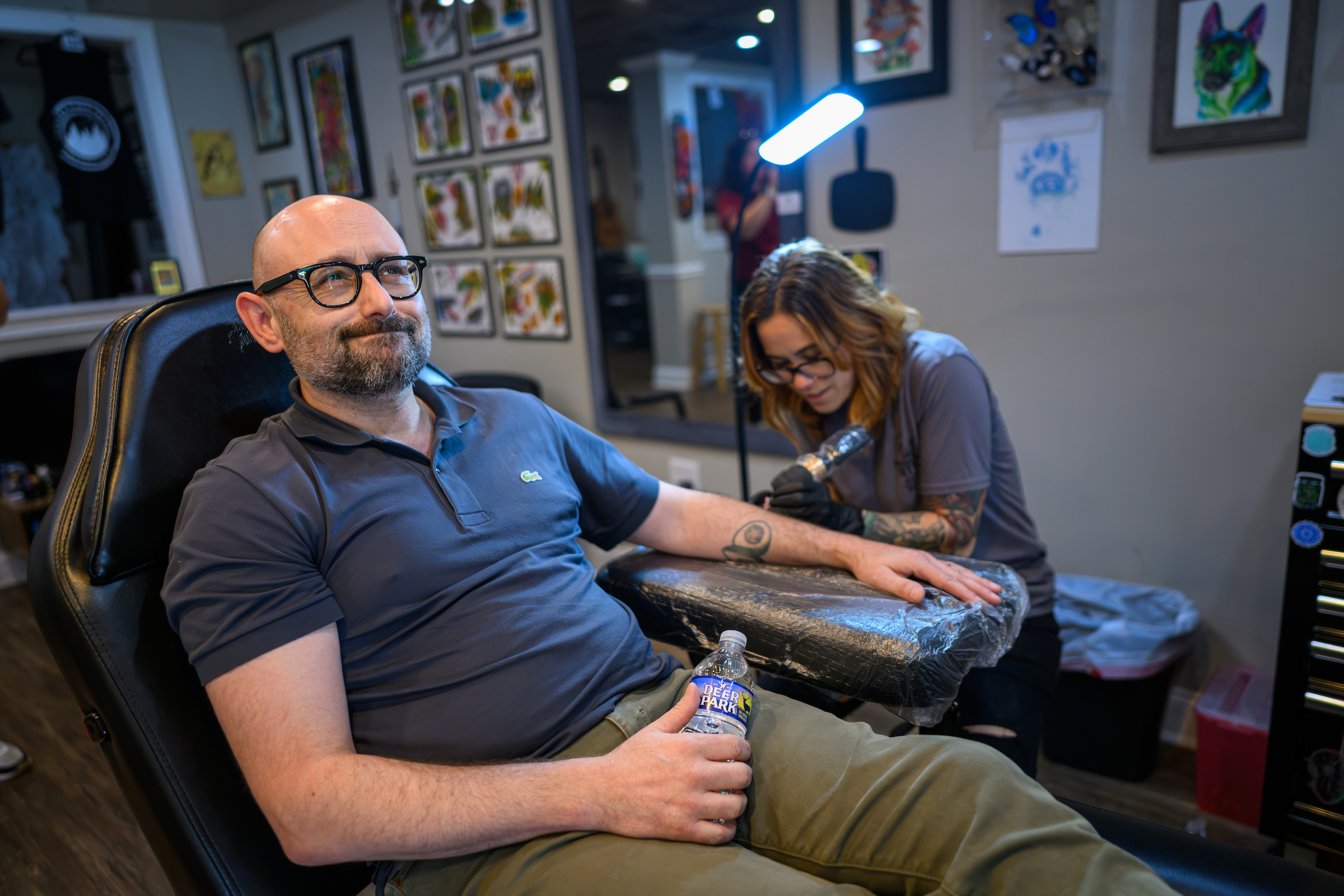 A man makes a face of discomfort while getting a tattoo.