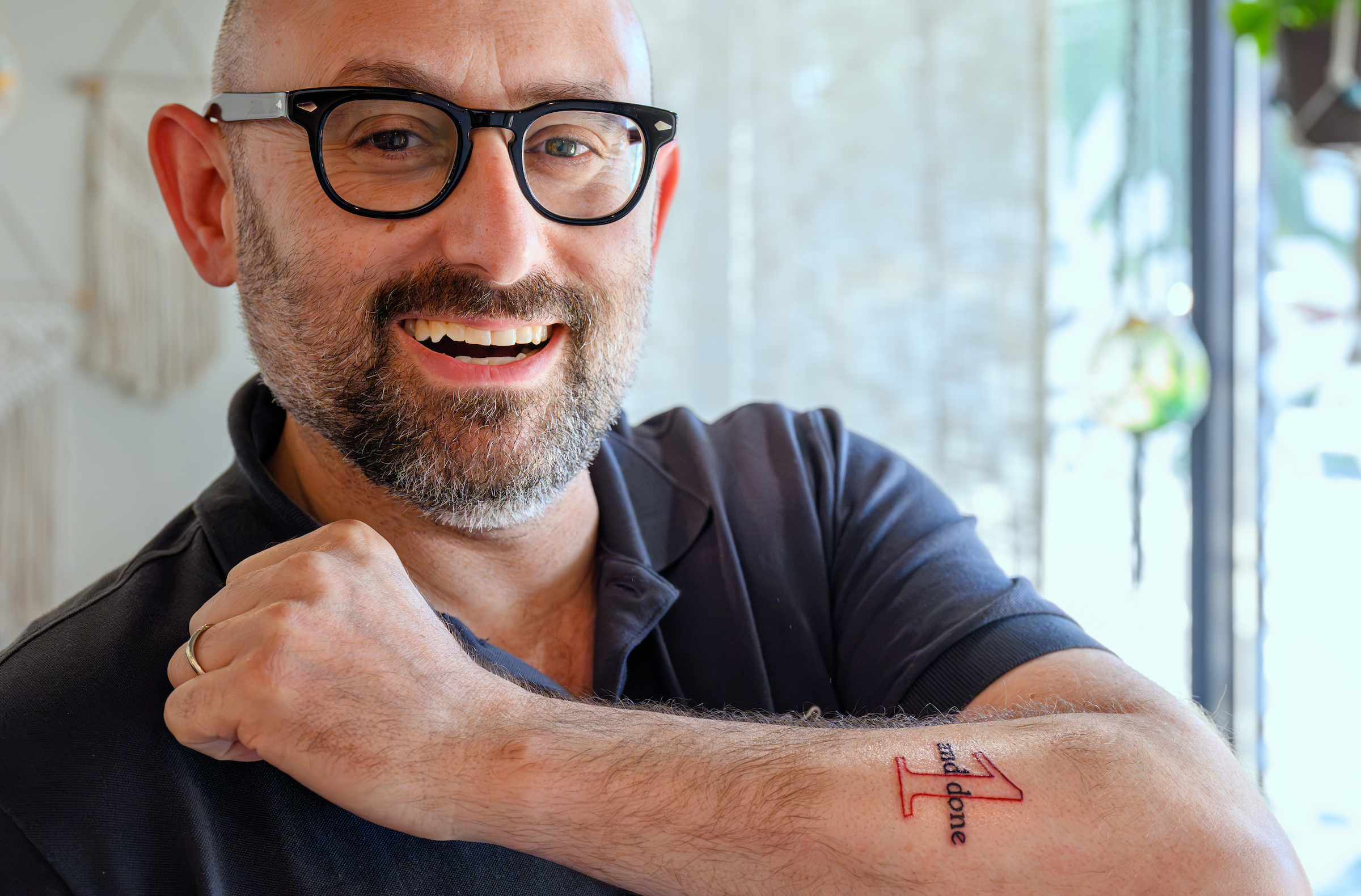 Dean Zak Kramer shows off the tattoo of his 1 and Done slogan, smiling