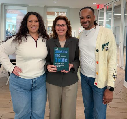 Stephanie Hernandez Rivera, Provost Rebecca Kohn, and Jonathan A. McElderry smiling, Kohn holding 'Still Shaking the Table.'