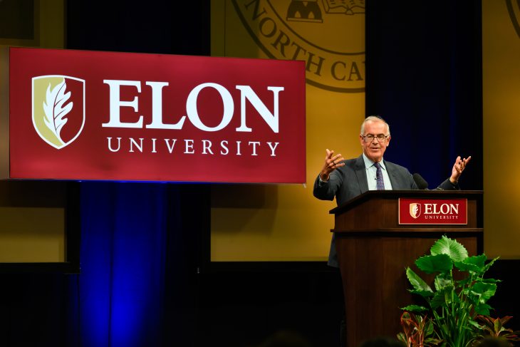 David Brooks gestures with both hands while speaking from an Elon University podium during Fall Convocation.