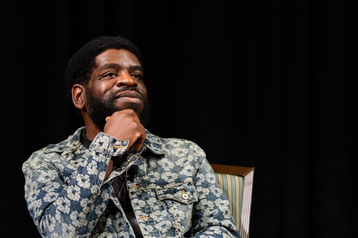     A guest speaker sits onstage with his hand resting beneath his chin during Elon University’s Common Reading lecture.