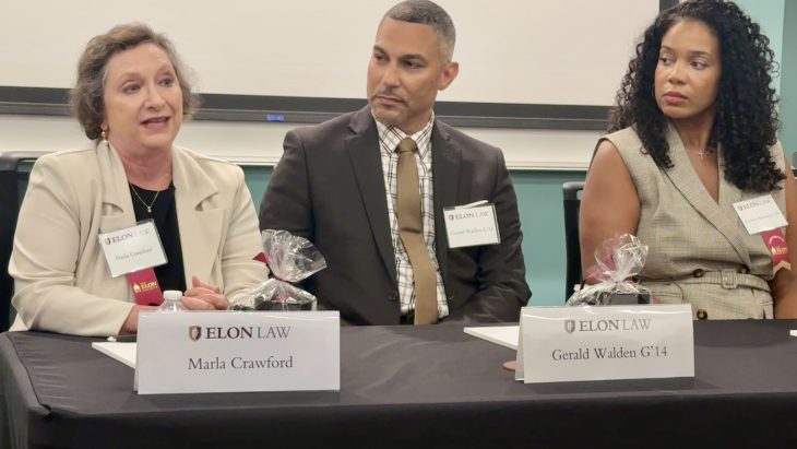 advisory board members seated behind a table. one of them is speaking