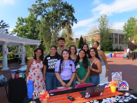 Maria Cassereau and El Centro student coordinators smiling at their table at Elon's 2026 Hispanic Heritage Month kickoff.