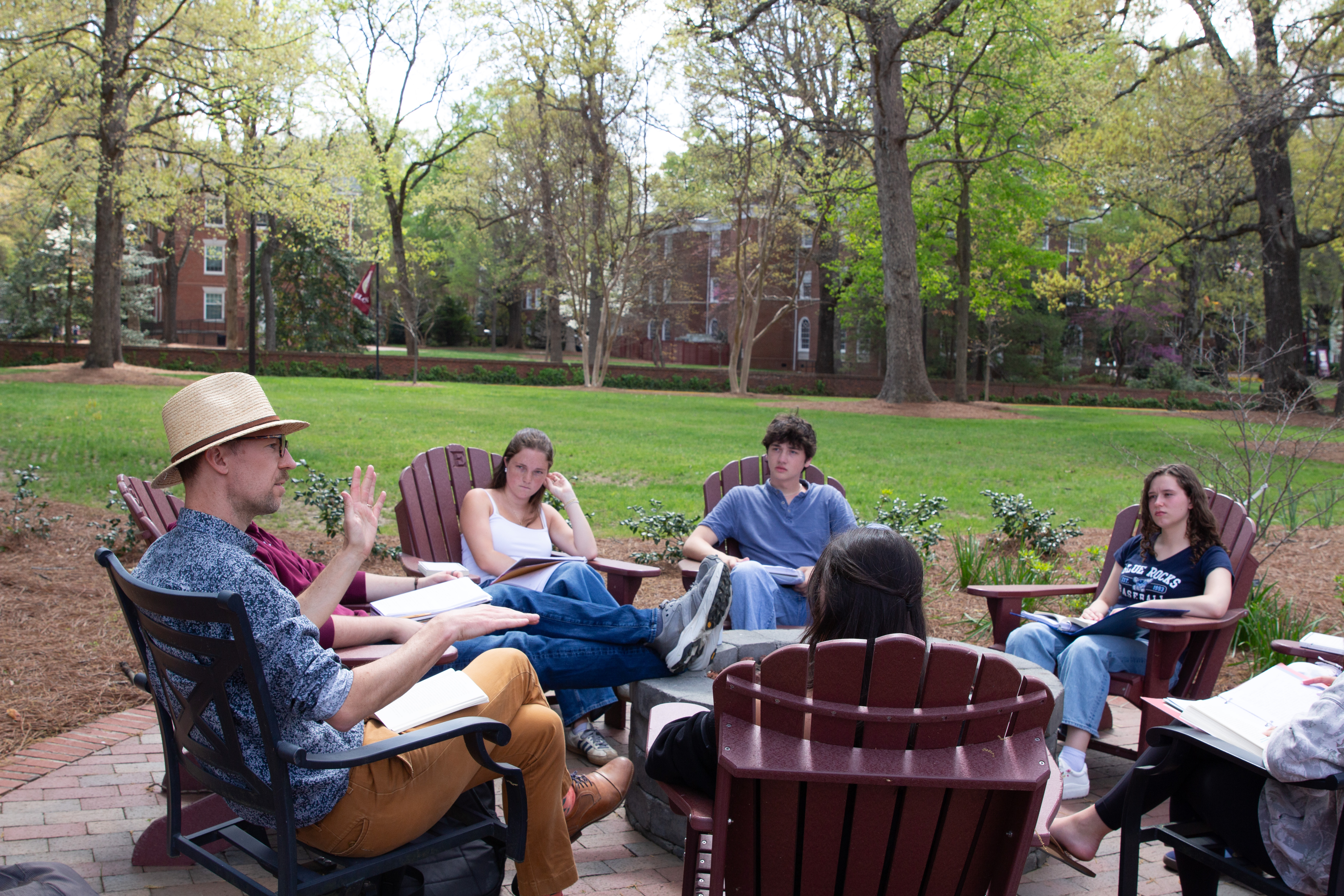 Ryan johnson, Associate Professor of Philosophy and Chair of the Department of Philosophy, sitting with a group of students outside teaching his philosophy class.