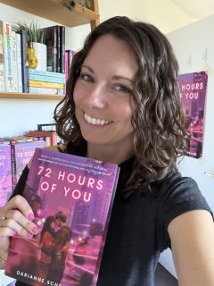 Darianne Schramm taking a selfie while holding her novel.