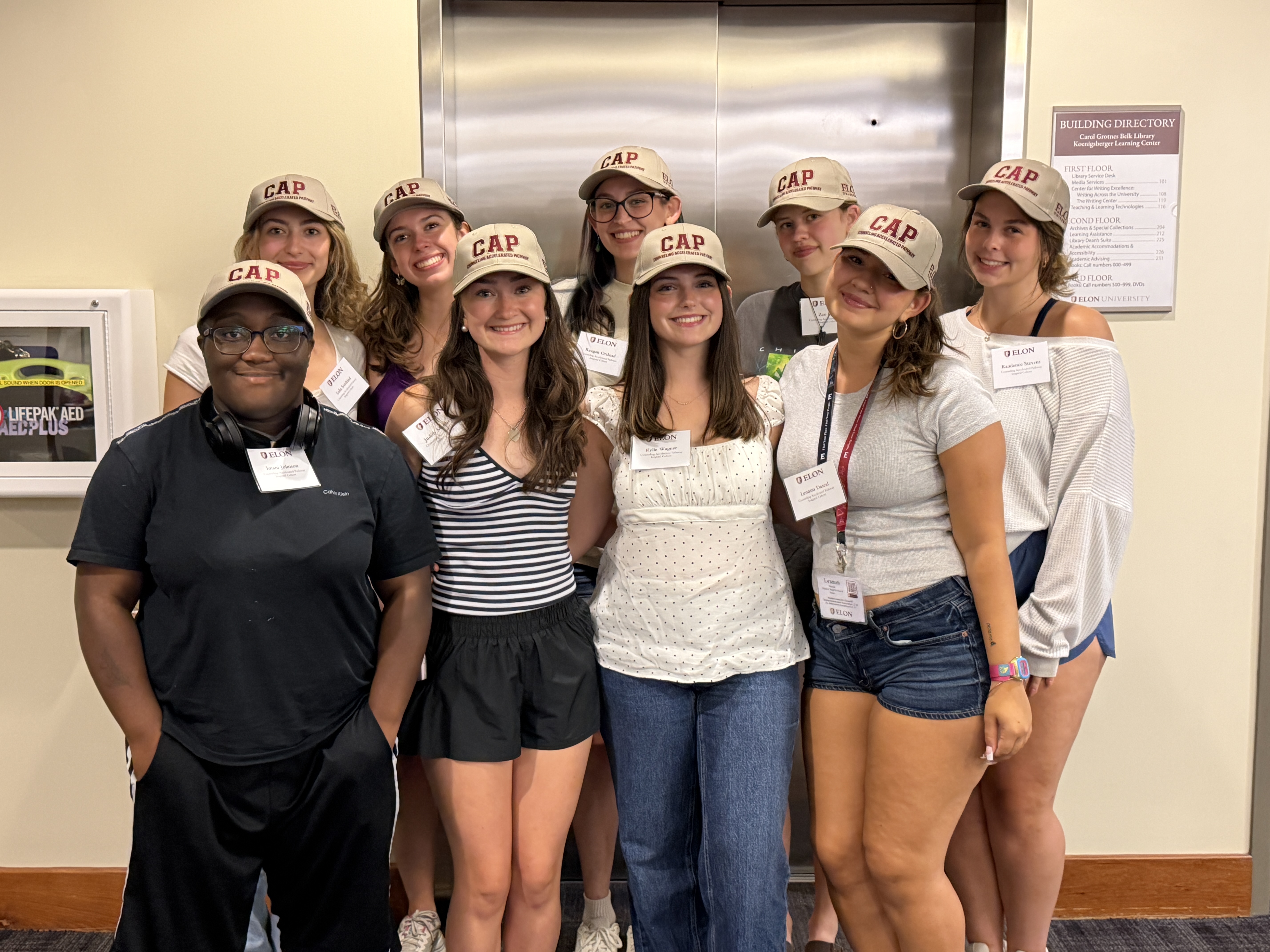 A group of people pose for a photo in front of an elevator