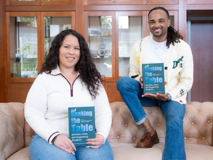 Stephanie Hernandez Rivera and Jonathan A. McElderry editors smiling and holding copies of their book, 'Still Shaking the Table: Activism, Unity, and Supporting Students.'