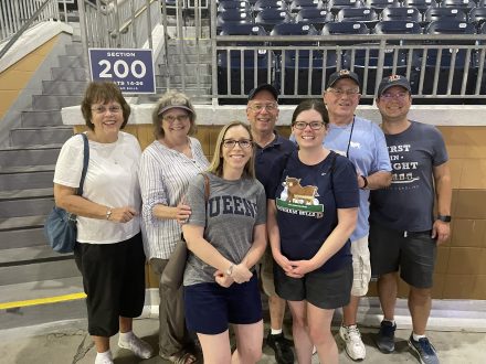 Fleming and Thoman stand in a stadium with five family members