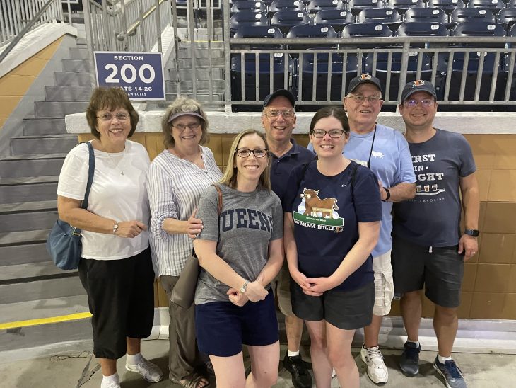 Fleming and Thoman stand in a stadium with five family members
