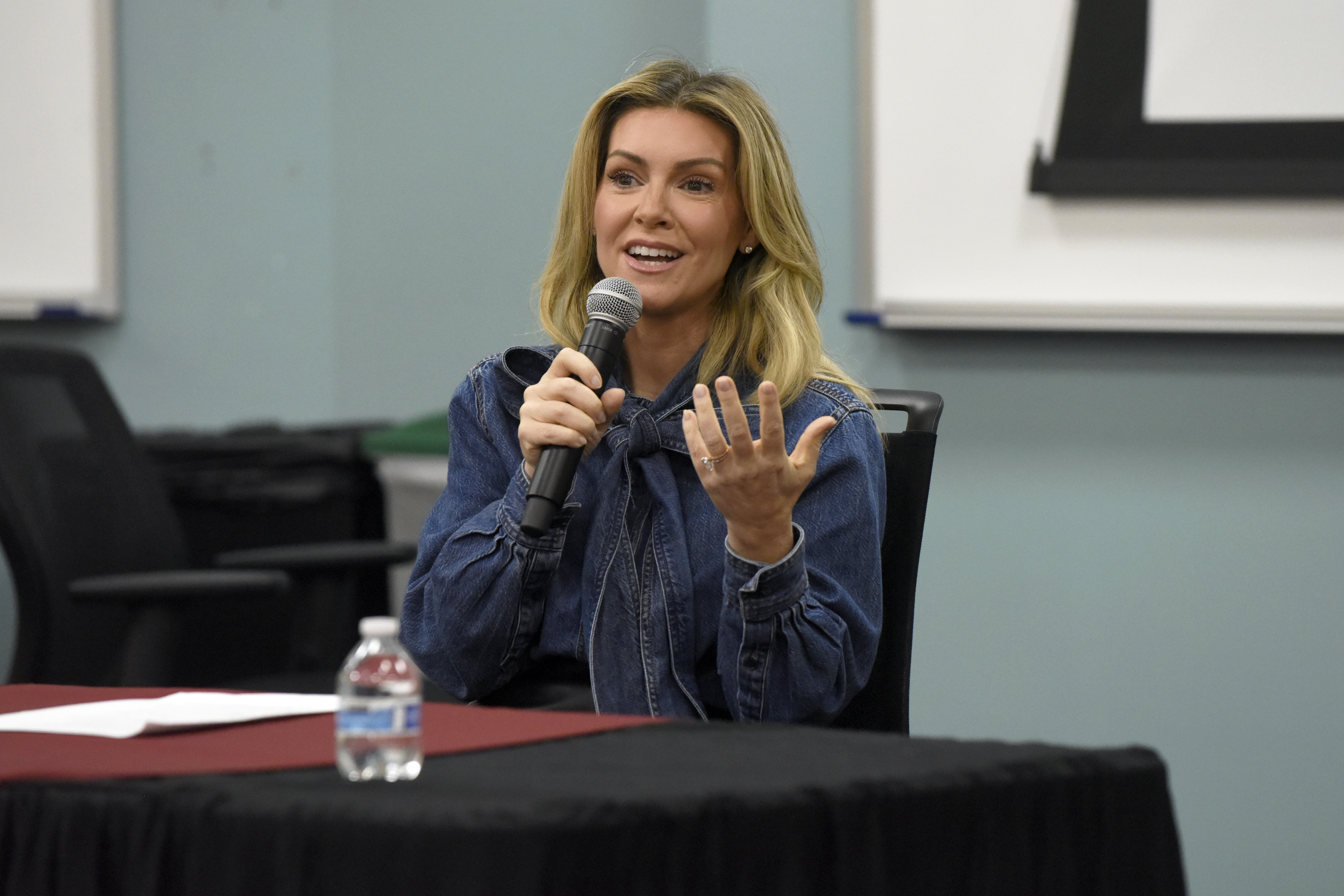 A photo of immigration attorney Hillary Walsh holding a microphone at a table in front of a classroom where the Elon Law Review's 2026 symposium was held on Sept. 26, 2026.