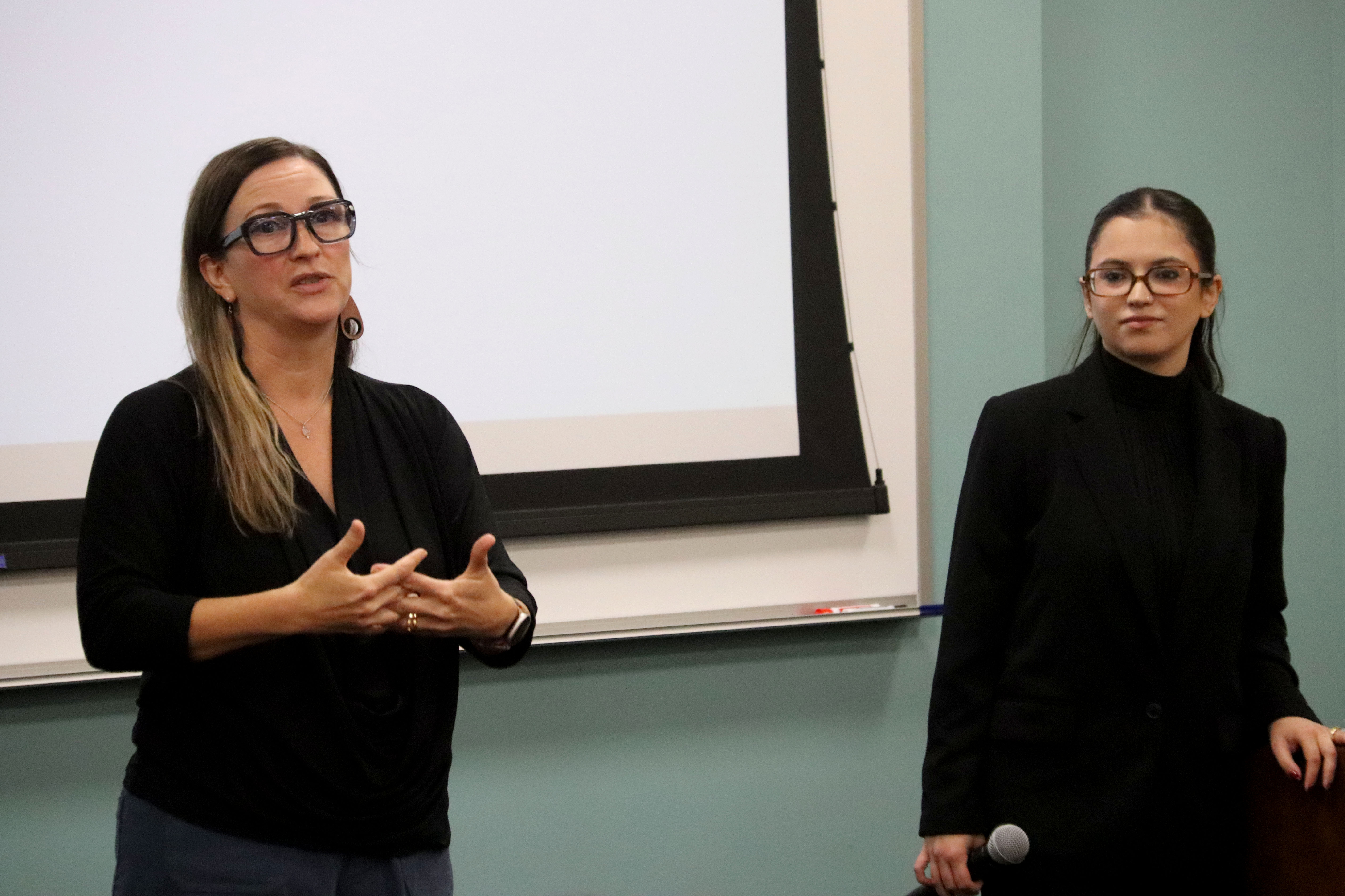 Heather Scavone, Assistant Professor of Law at Elon Law and former Associate Counsel at the Department of Homeland Security, U.S.C.I.S., addresses symposium attendees with with Elon Law alumna Dara Arroyo-Longoria L’22, Attorney at McKinney Immigration Law, looking on.