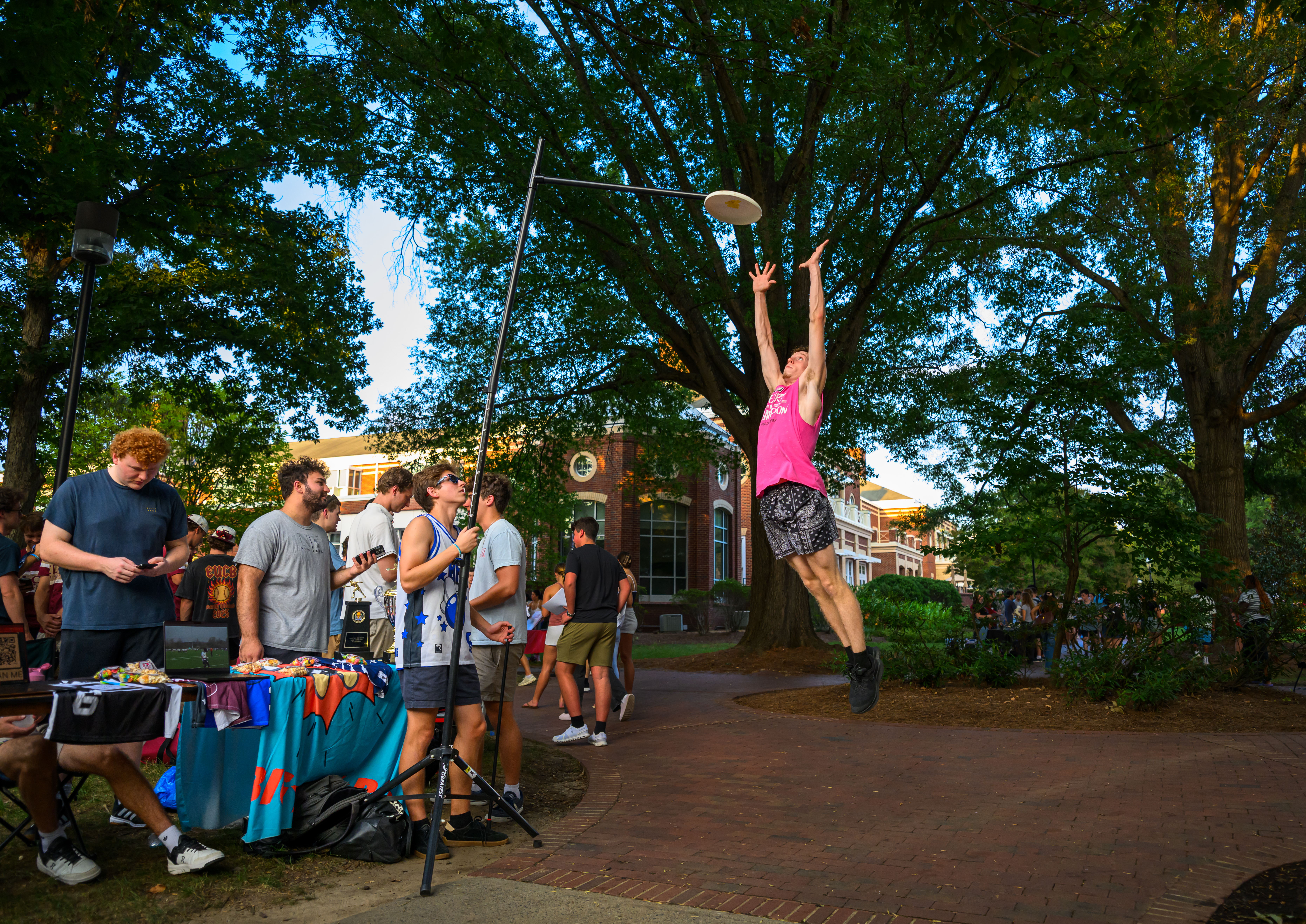 A student leaps to catch a flying disc during the Fall Organization Fair as students gather around tables on Young Commons.