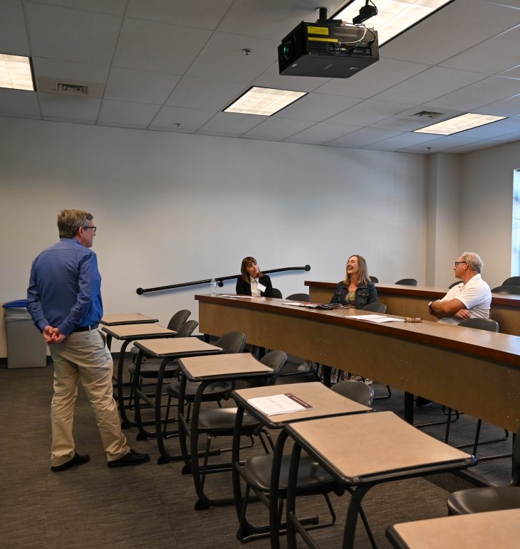 A facilitator speaks with three attendees during a breakout discussion.