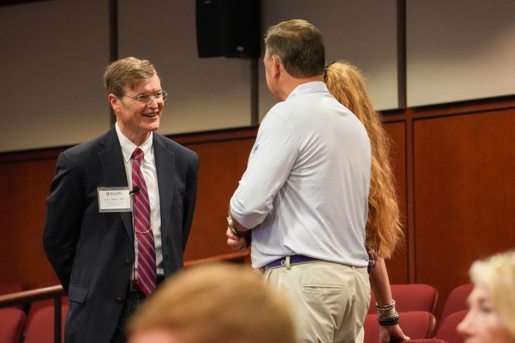 Steve Miller smiles while talking with two attendees.
