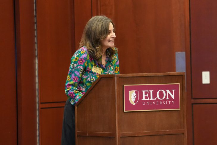 Haya Ajjan speaks from a podium with an Elon University sign.