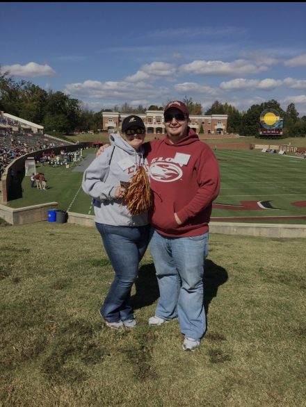 Kat Wallace and her husband, Chris Wallace ’06, stand together overlooking Rhodes Stadium during a visit to Elon University.
