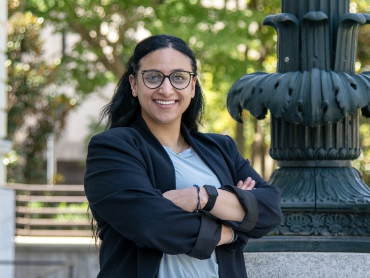 Mayar Elgeyoshi smiles with her arms folded in front of the Old Guilford County Courthouse.
