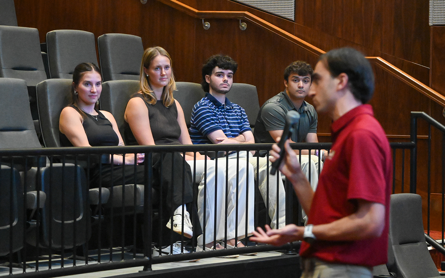 Four Elon students sit in Turner Theatre listing to Anthony Bamford.