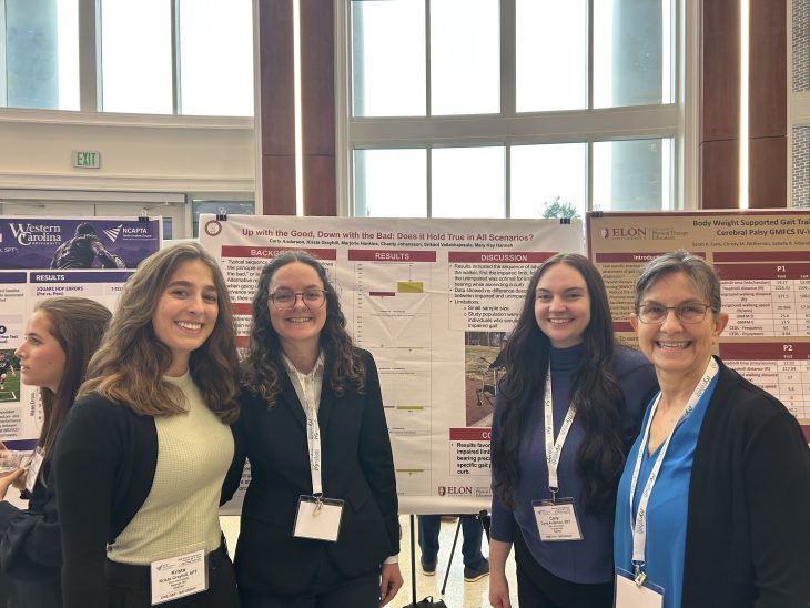 Group posing before their poster