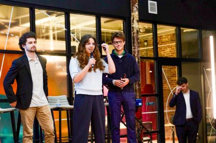 Gabi Czerveny ’27 speaks into a microphone while two Transfer Ready teammates stand beside her.