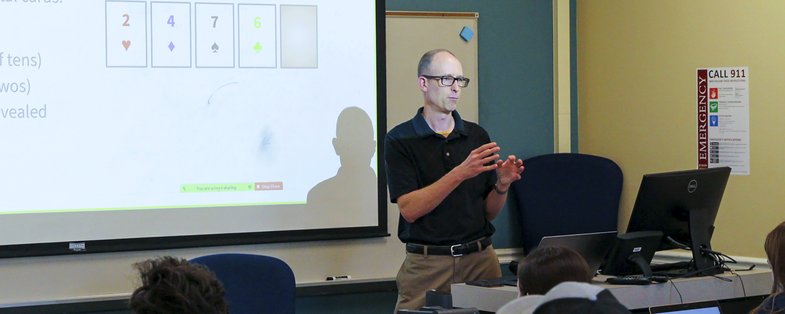 Professor of Computer Science Duke Hutchings teaching in front of a projector screen.
