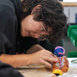 Student placing part on anime charecter