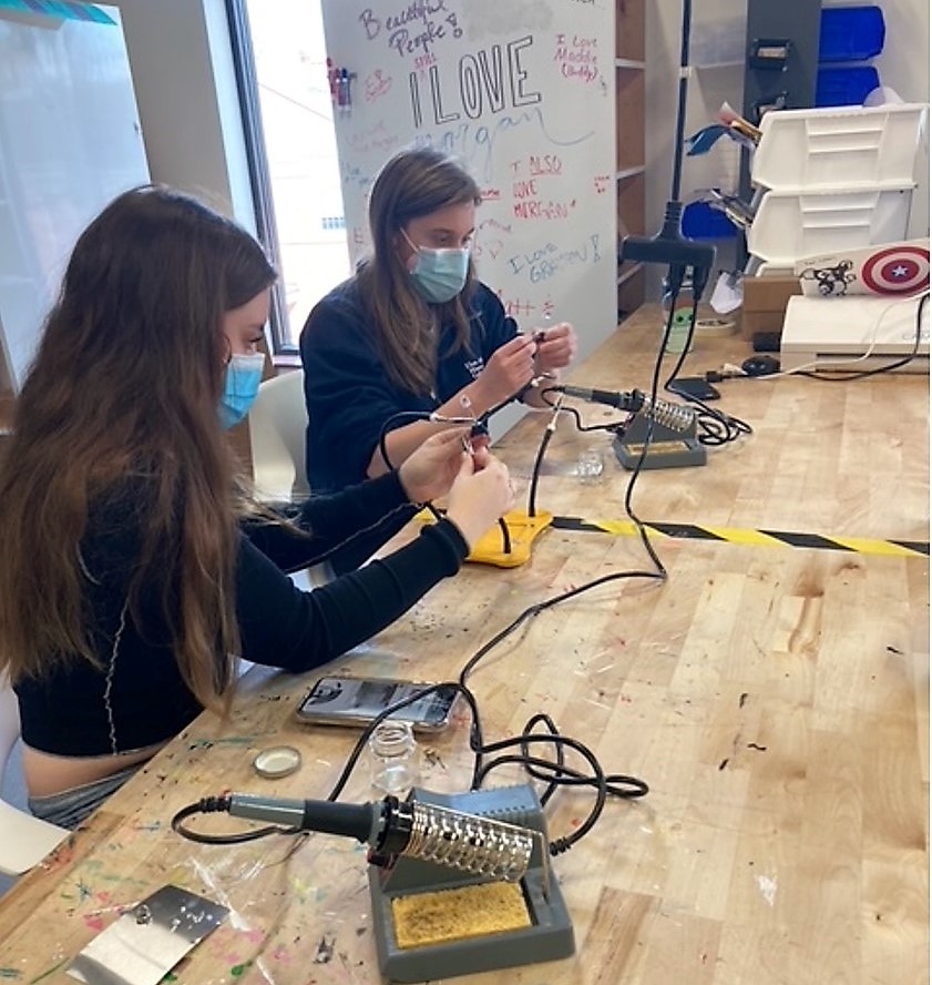 Two students soldering their electronics