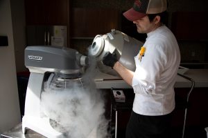 Chef pouring liquid nitrogen into an ice cream mixer