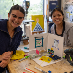 Two students posing with their model house