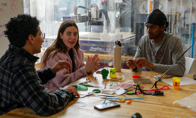 3 students discussing around a table.