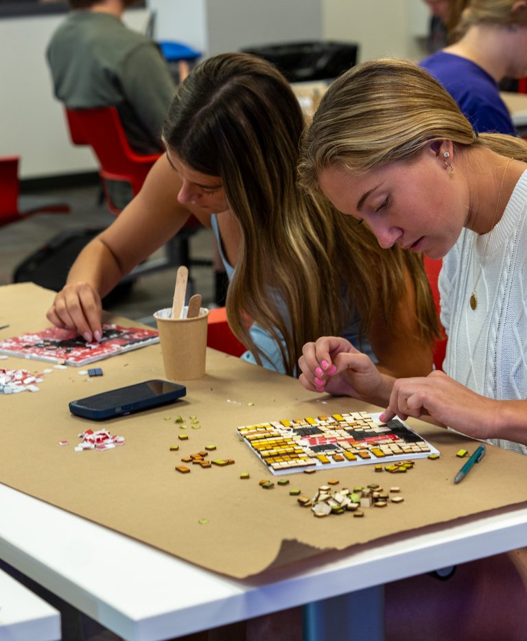 2 students making their mosaics at a table