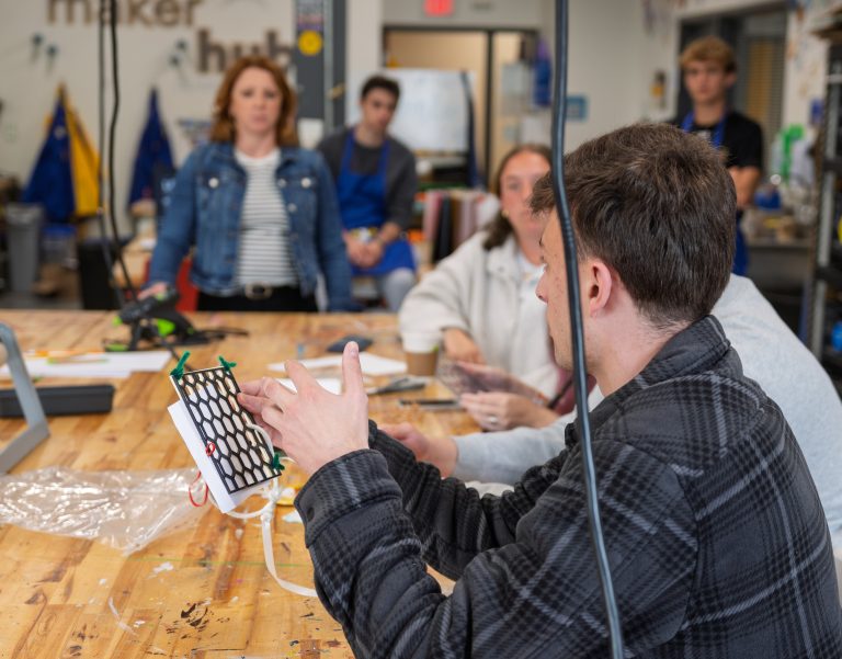 Student discussing their first prototype as the professor looks on.