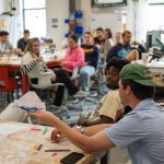 Students showing their first prototype as the class looks on.