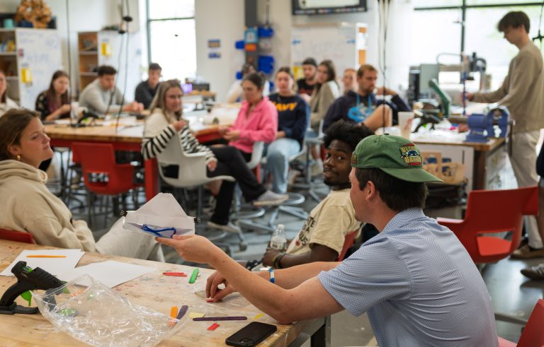 Students showing their first prototype as the class looks on.