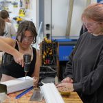 Student drilling hole inside device, made from aluminum rain gutters.