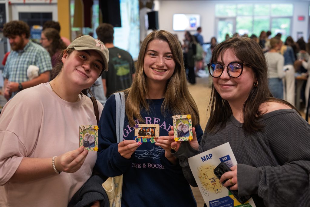 Three students holding up a picture frame they made