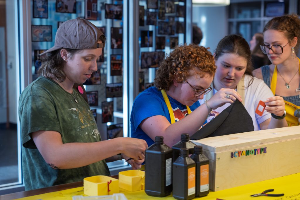 Students pulling up fabric cloth to look into a box