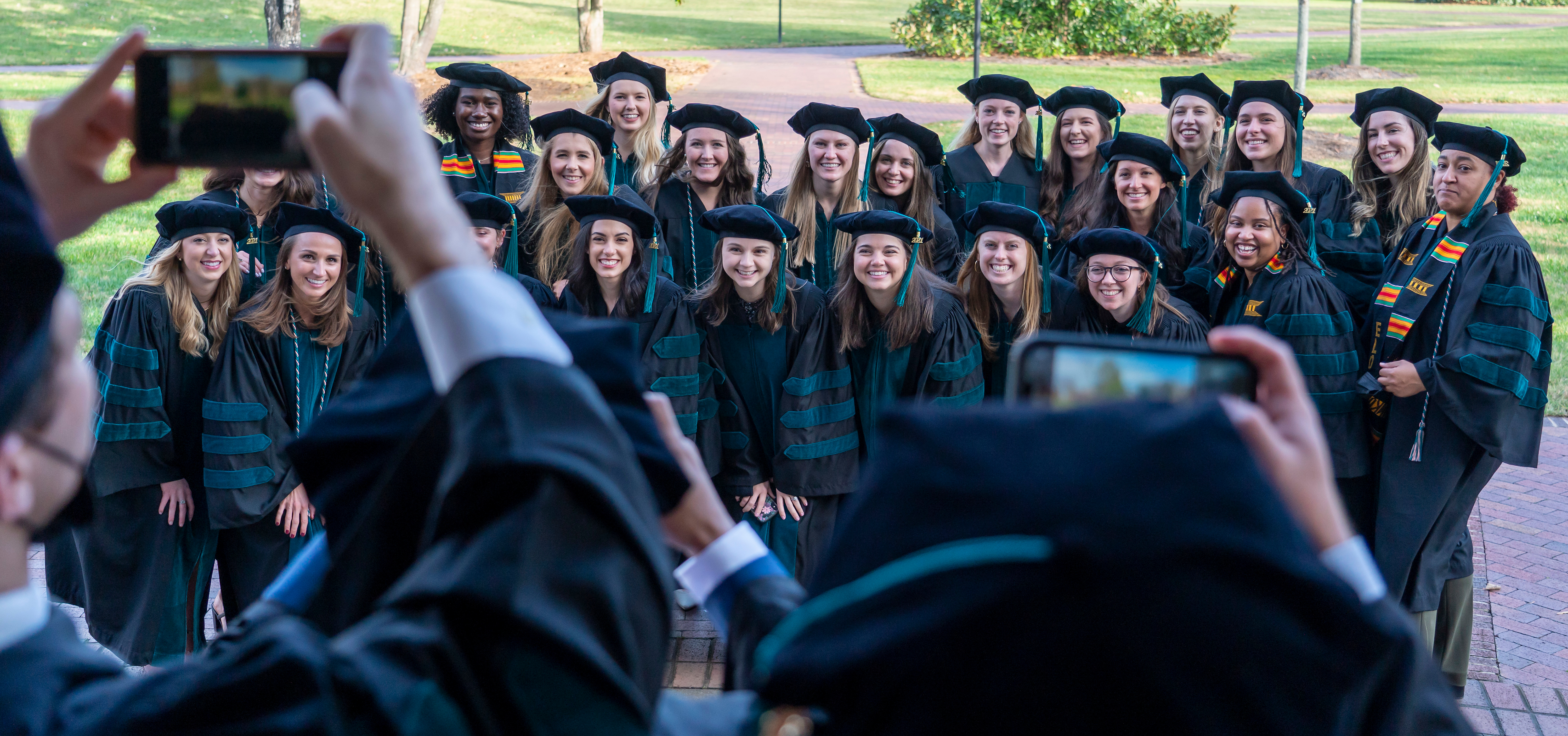 a group of Elon University graduate program students posing for a picture in their regalia