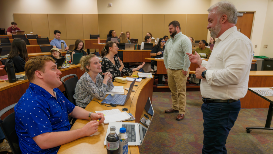 A classroom of students speak with a professor casually during a break. Students in a courthouse being sworn in as licensed attorneys. PreLaw Magazine names Elon Law is one of the best law schools in NC for practical training.