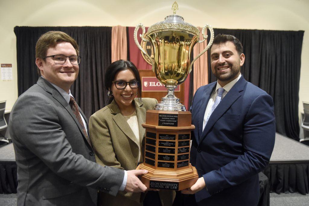 Three Elon Law students holding the Chief Justices Cup at Elon Law.
